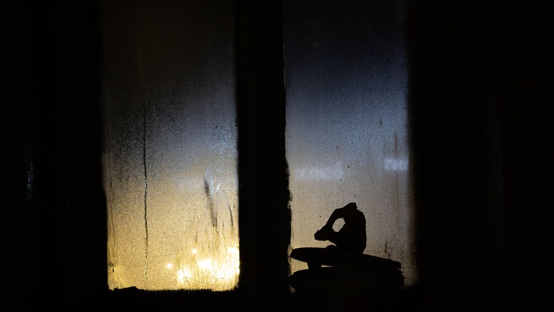 A person's silhouette beside a wet, foggy window at night