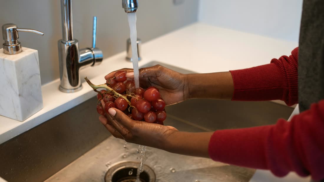 Fresh grapes being washed in a kitchen sink