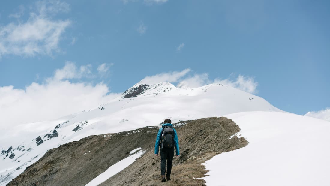 A hiker walking through snowy mountains
